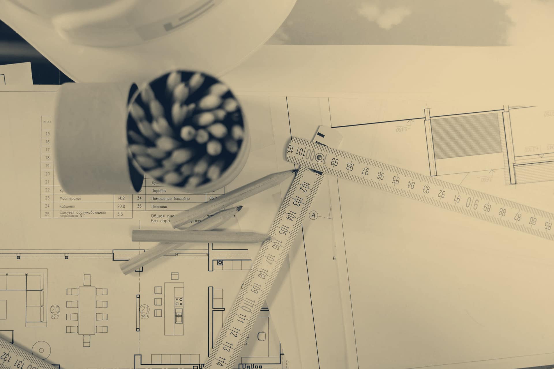 Plans d'architecte sur une table, règle pliante et crayons.